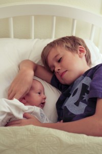 A family created by birth and adoption. Eleven-year-old Skylar cuddling in bed with adopted baby Bodhi