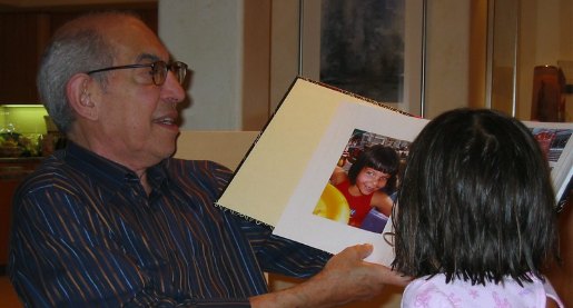 Older man viewing a photo book with a child
