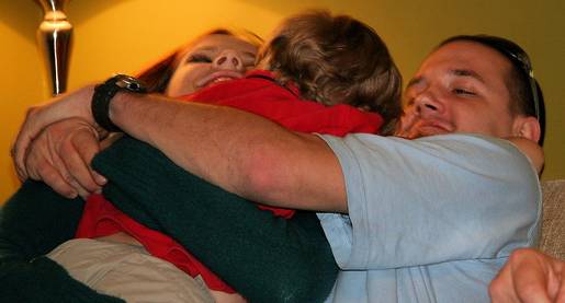 man and woman hugging young child together