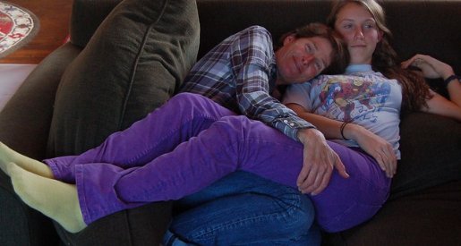 Mom and teen daughter snuggling on the couch