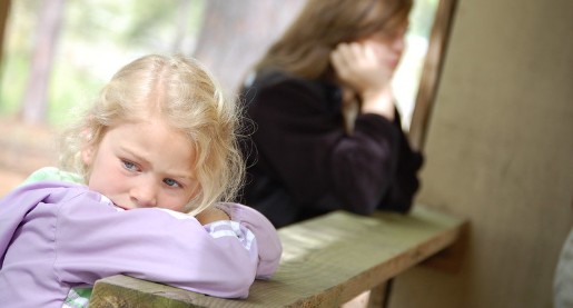 Young girl with her head on her arms, leaning against a rail