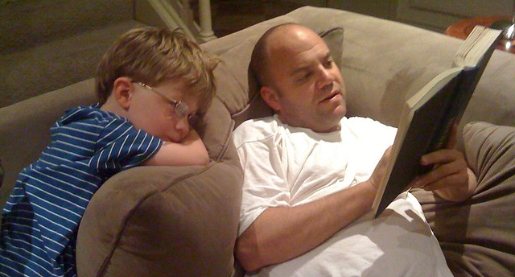 Dad reading to son, sitting on couch