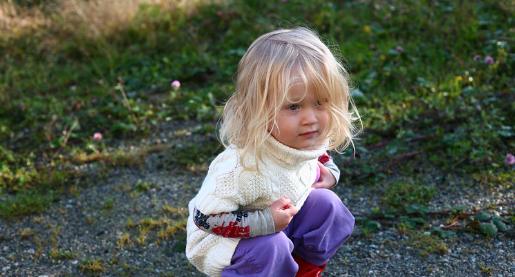 toddler squatting on the ground outside
